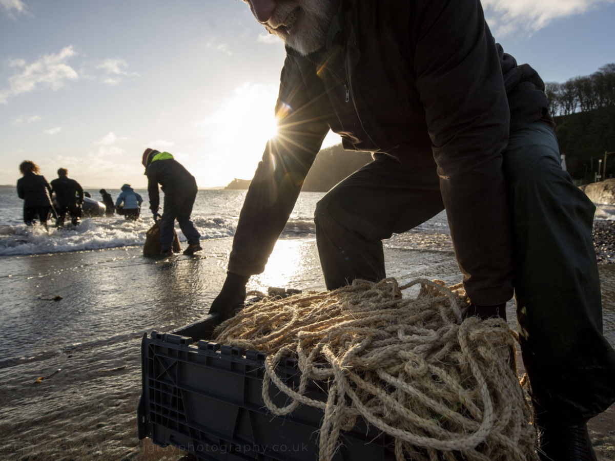 Volunteers carrying seagrass planting materials into the sea at Dale Bay